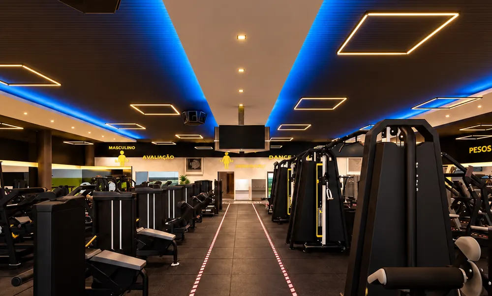 Salão de musculação da UaiFit com máquinas modernas e iluminação de LED